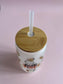 Tumbler with wooden lid and straw on a pink background