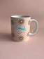 Beige mug with 'Good Vibes' text and flower designs on a pink background